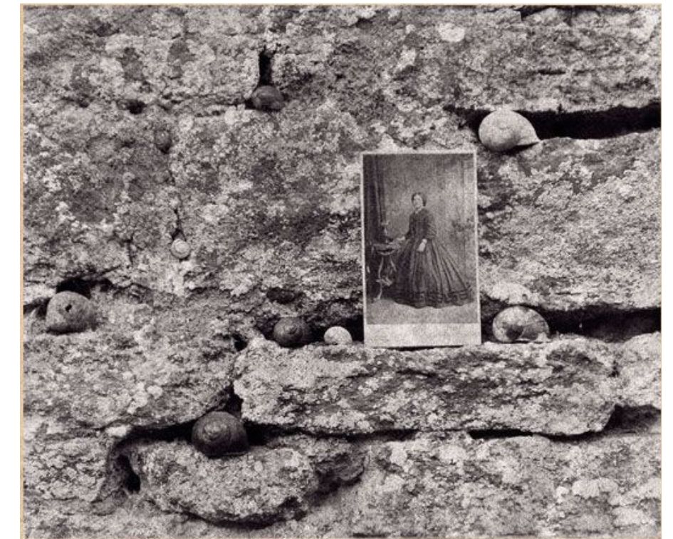 old photograph of the lady standing on the stony wall